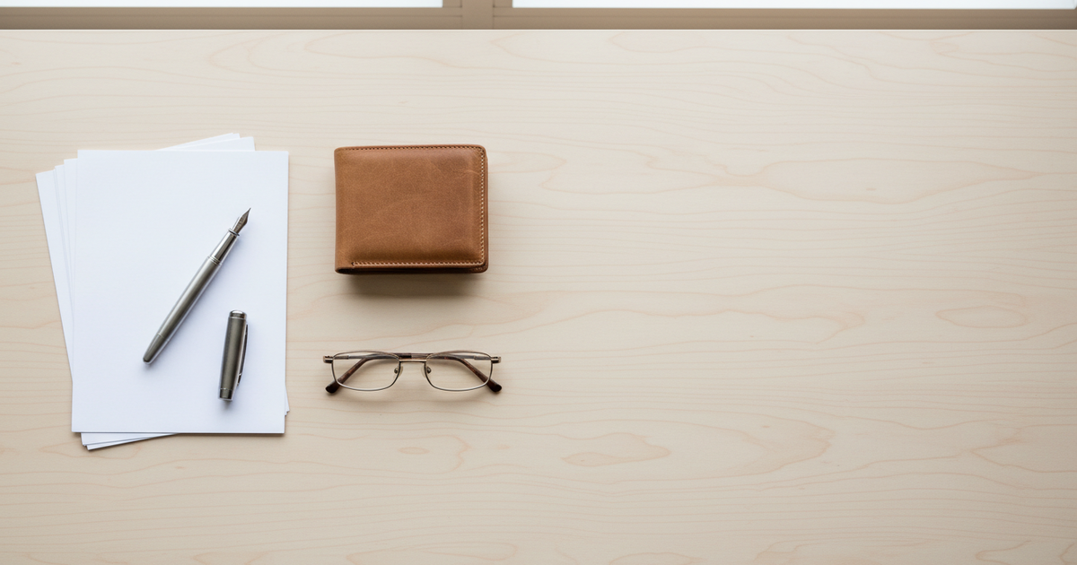 Items laid out for a notary appointment: paperwork, a pen and a wallet on a desk.